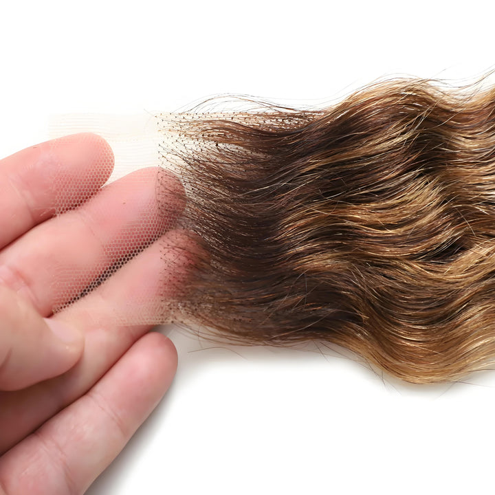 Close-up of HD lace on 2×6 deep wave lace closure in medium brown with honey blonde highlights, displayed on hand for lace detail clarity.