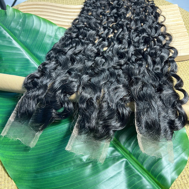 Multiple bundles of 2×6 water wave lace closures in natural color arranged on display with defined curls.