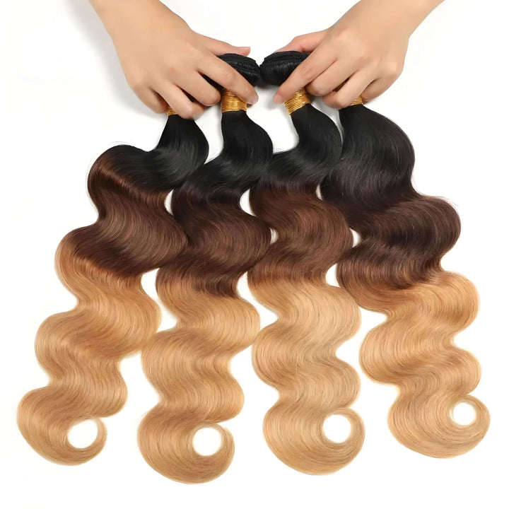 Four T1B/4/27 body wave bundles held in hand, showing ombre effect from dark roots to medium brown and honey blonde tones.