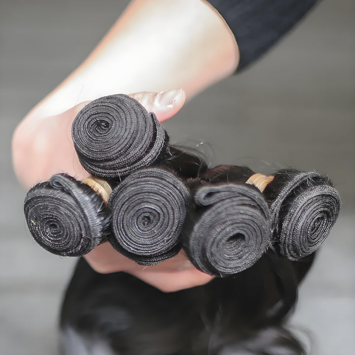 Shiny natural black body wave bundles held in both hands, highlighting silky wave pattern and full thickness from top to end.
