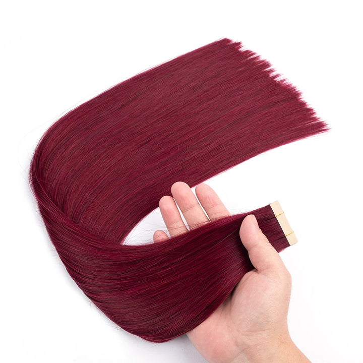 Close-up of straight burgundy wine red tape in hair extensions held in hand, showing silky strands and adhesive tops.