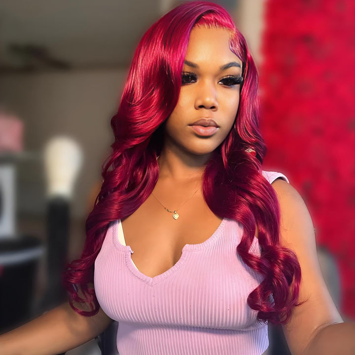 Model in pink top wearing full lace body wave wig in dark burgundy (99J), styled in loose voluminous waves.
