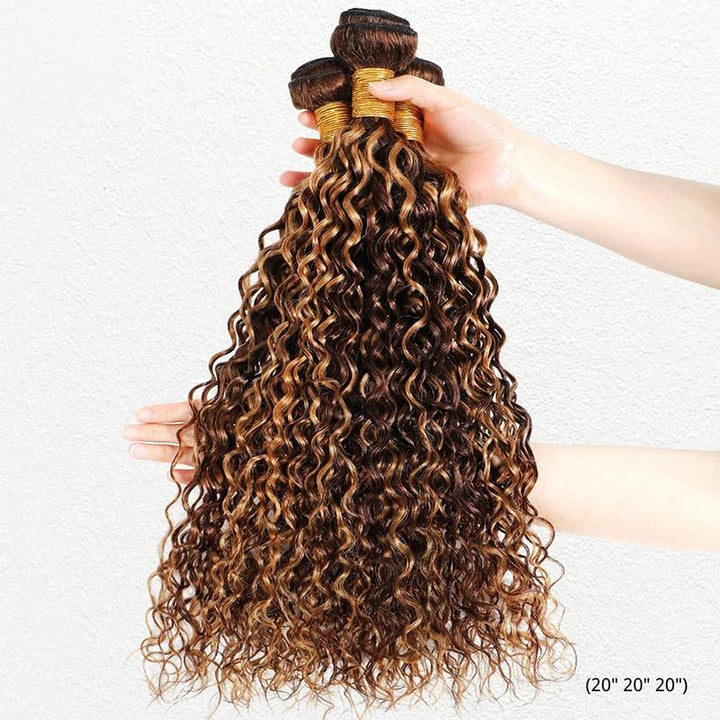 Hand holding three honey blonde deep wave bundles showing spiral curls and dimensional color.