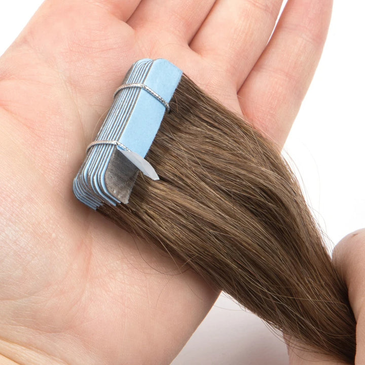 Close-up of silky texture and blue adhesive tabs on straight chocolate brown tape-in hair extensions.