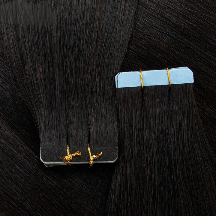 Two stacks of straight tape-in extensions laid flat, secured with gold ties and showcasing aligned tips and tape base.